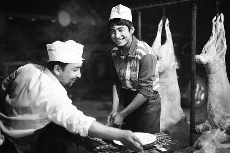 uyghur man making kebabs