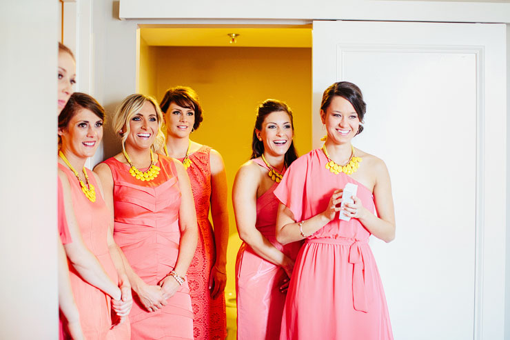 bridesmaids watching bride put on wedding gown